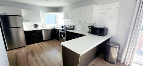 eine Küche mit weißen Arbeitsflächen und einem Kühlschrank aus Edelstahl in der Unterkunft Cochrane Diggs in Cochrane
