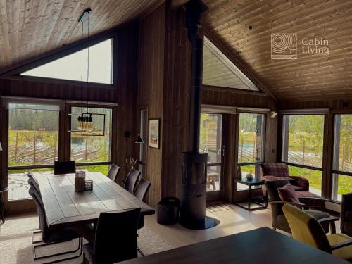 uma sala de jantar com mesa, cadeiras e janelas em Modern unique cabin fantastic location Skeikampen em Svingvoll