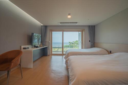 a hotel room with two beds and a television at Seaore Resort in Seogwipo