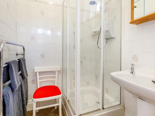 a bathroom with a shower and a sink and a red stool at Clooneavin Apartment 2 in Lynmouth