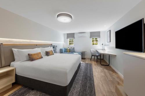 a bedroom with a bed and a desk and a tv at Crowne Plaza Hawkesbury Valley by IHG in Windsor