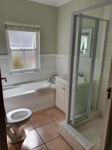 a bathroom with a tub and a toilet and a shower at 4236 River Club in Plettenberg Bay
