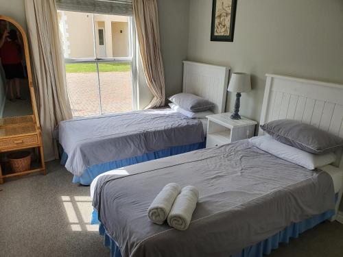 two beds in a room with a window at 4236 River Club in Plettenberg Bay