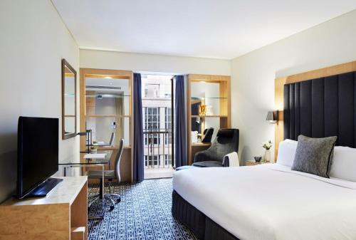 a hotel room with a bed and a flat screen tv at Sofitel Sydney Wentworth in Sydney