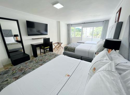 a hotel room with two beds and a flat screen tv at Hotel Arhuaco Rodadero in Santa Marta