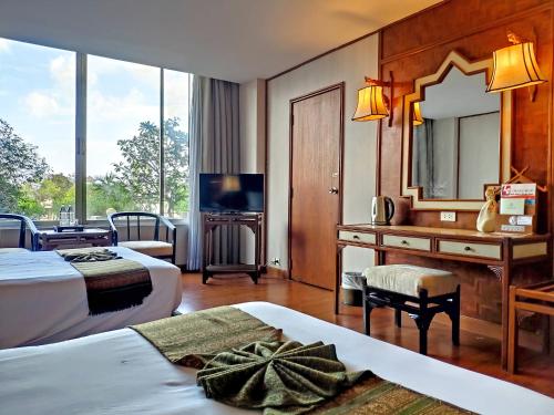 a hotel room with two beds and a desk with a mirror at Chiang Mai Orchid Hotel SHA EXTRA PLUS in Chiang Mai