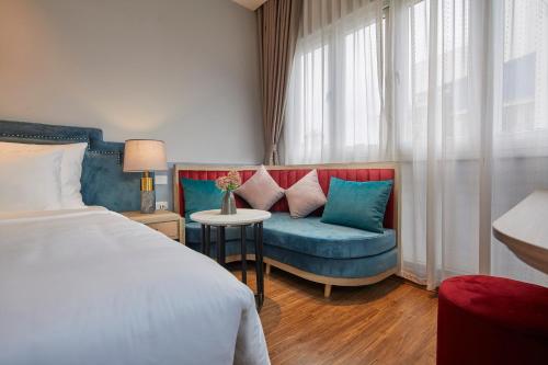 sypialnia z łóżkiem, niebieską kanapą i oknem w obiekcie HANOI FLORA HOTEL w mieście Hanoi