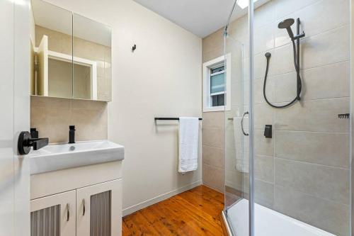 a white bathroom with a sink and a shower at SandyPotato Your Beach Home in Potato Point