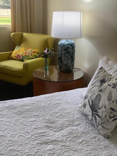 a bedroom with a bed and a lamp and a chair at Temora Motel in Temora