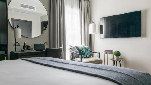 a hotel room with a bed and a desk and a mirror at The Selwyn, Richmond in Richmond upon Thames