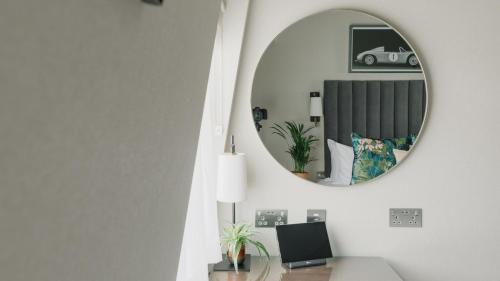 a mirror on a wall above a desk in a room at The Selwyn, Richmond in Richmond upon Thames