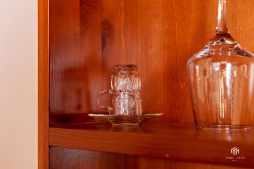 a glass cup on a shelf next to a bottle at VINGT-DEUX Vouni 22 in Vouni
