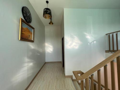 a hallway with a clock on the wall and a staircase at 92 Chiangrai poshtel in Ban Fang Min