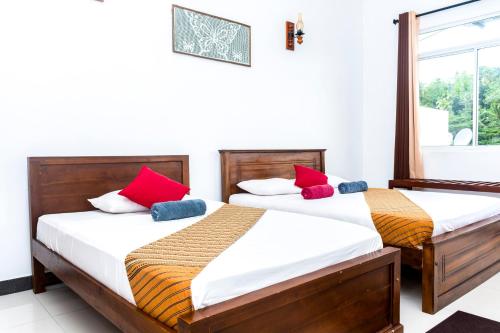 1 dormitorio con 2 camas y almohadas rojas y azules en Kandy Riverside Villa, en Kandy