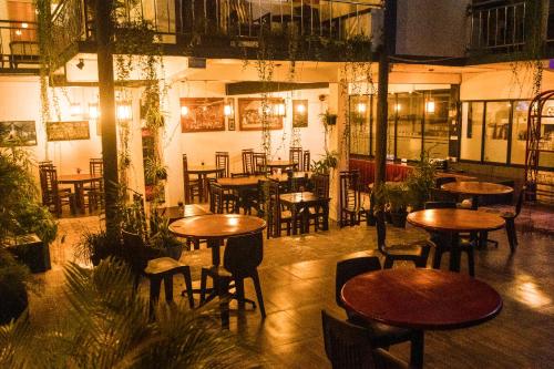 a restaurant with wooden tables and chairs and plants at Kandy Riverside Villa in Kandy