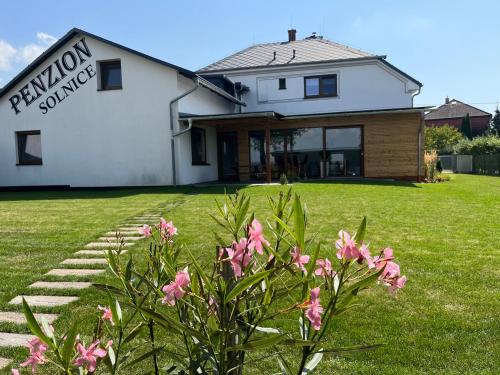 a white house with pink flowers in front of it at Penzion 411 in Solnice