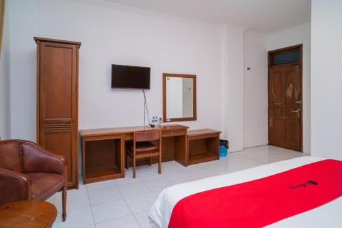a bedroom with a bed and a desk and a mirror at RedDoorz Plus at Hotel Surya Solo in Solo