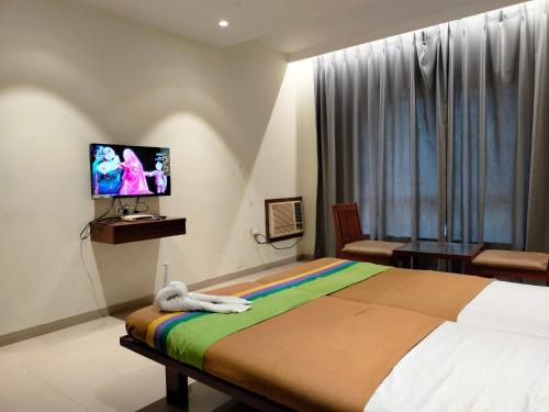 a bedroom with a bed and a flat screen tv at Hotel Sumanchandra Suites in Nashik