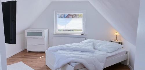 a small white bedroom with a bed and a window at Ferienhaus Strandallee 8 in Burhave