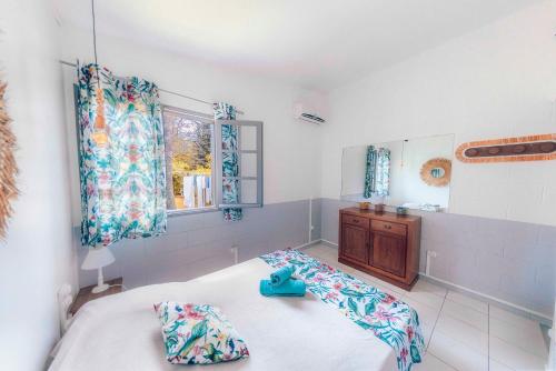 um quarto com uma cama, uma janela e um espelho em Bungalow PITAYA dans jardin tropical proche lagon em Saint-Gilles-les-Bains