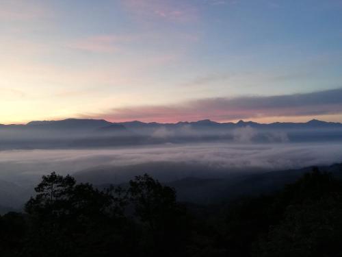 a view of a foggy valley at sunset with mountains at Fujio Pension Madarao Apartment Hotel & Restaurant in Iiyama