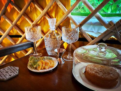a table with wine glasses and a plate of food at Traditional YURT @ Longleat in Warminster