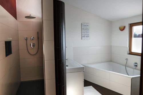 a bathroom with a tub and a sink and a shower at Ferienwohnung Amboss in Grünkraut