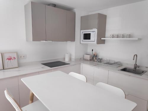 uma cozinha com armários brancos e uma mesa e cadeiras brancas em Apartamentos CANDEA em Lugo