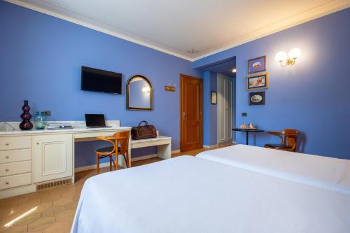 a bedroom with blue walls and a bed and a desk at Hotel San Luca in Spoleto