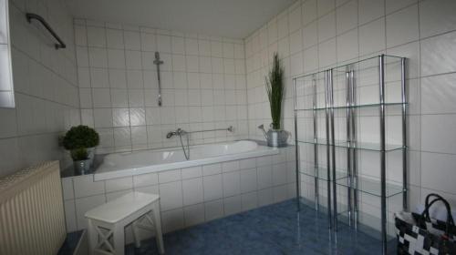 a white tiled bathroom with a tub and a sink at Ferienwohnungen Huus Diekenblick in Butjadingen