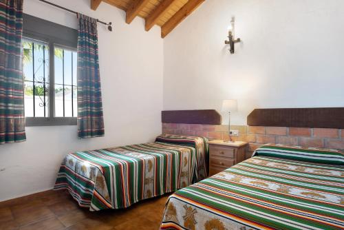 a bedroom with two beds and a cross on the wall at Casa Alberto in Zahora