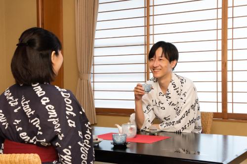 a woman sitting at a table talking to a man at Hotel Hagoromo in Shizuoka
