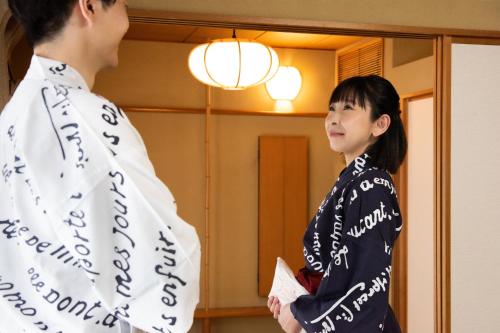 a woman standing next to a man in front of a mirror at Hotel Hagoromo in Shizuoka
