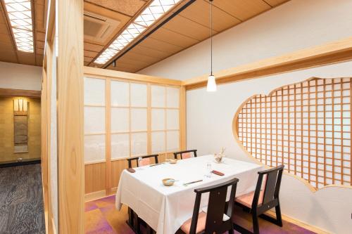 a dining room with a white table and chairs at Hotel Hagoromo in Shizuoka
