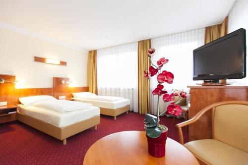 a hotel room with two beds and a flat screen tv at Hotel am Berliner Platz in Langenfeld
