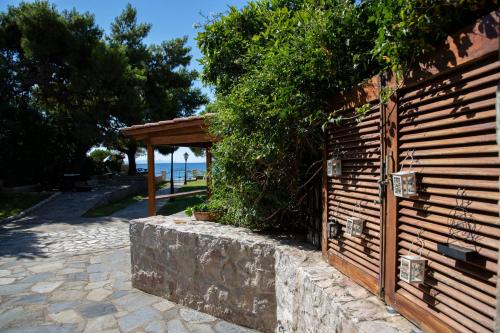 a wooden fence next to a stone wall with a pavilion at Seaside Haven Kineta in Kineta