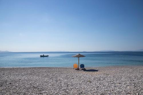 una silla y una sombrilla en una playa en Seaside Haven Kineta, en Kineta