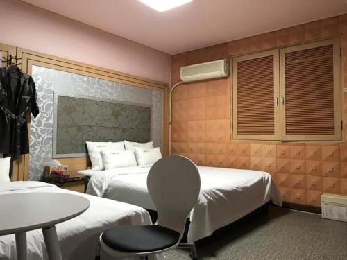 a hotel room with two beds and a table and a chair at Sharp Hotel Jeonju in Jeonju