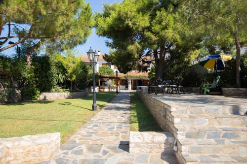 a stone walkway with an umbrella in a yard at Seaside Haven Kineta in Kineta