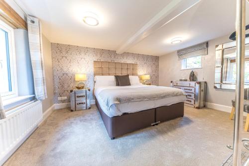 a bedroom with a large bed and two windows at Sandbeds Farmhouse in Kendal