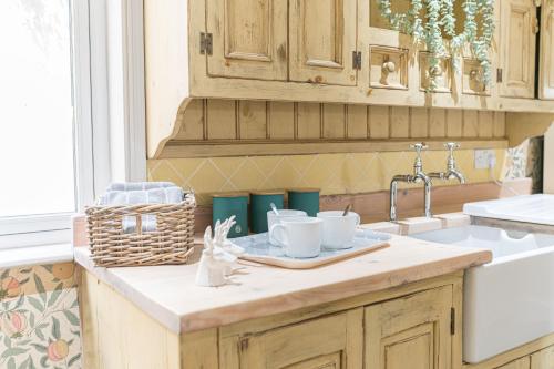 a kitchen counter with two cups and a sink at Sandbeds Farmhouse in Kendal