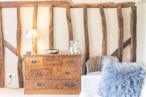 a bedroom with a wooden dresser and a lamp at Sandbeds Farmhouse in Kendal