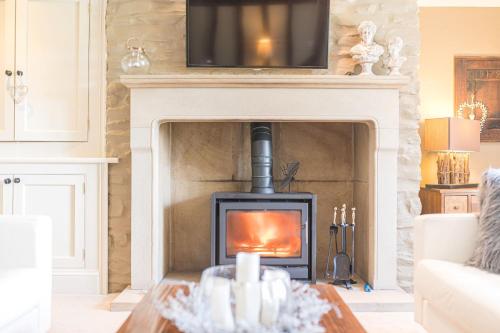 a living room with a fireplace with a television above it at Sandbeds Farmhouse in Kendal