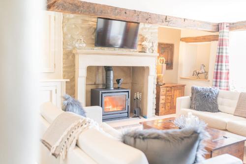 a living room with a fireplace with a tv above it at Sandbeds Farmhouse in Kendal