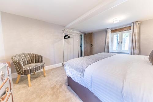 a bedroom with a bed and a chair and a window at Sandbeds Farmhouse in Kendal