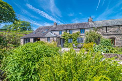 an old stone house with a garden in front of it at Sandbeds Farmhouse in Kendal