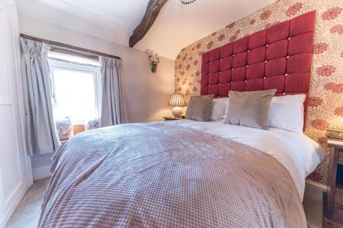 a bedroom with a large bed with a red headboard at Sandbeds Farmhouse in Kendal