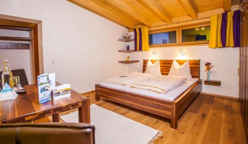 a bedroom with a bed and a desk and a table at Simone's Platzerl - inklusive täglichem freien Eintritt Tauern Spa - nur 5 Gehminuten, Sommerkarte, privatem Garten mit Schwimmteich, Grill und Saunabereich in Kaprun