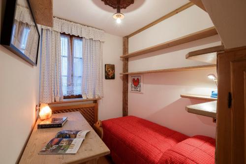 una piccola camera con letto rosso e tavolo di Villa Marianna - Stayincortina a Cortina dʼAmpezzo