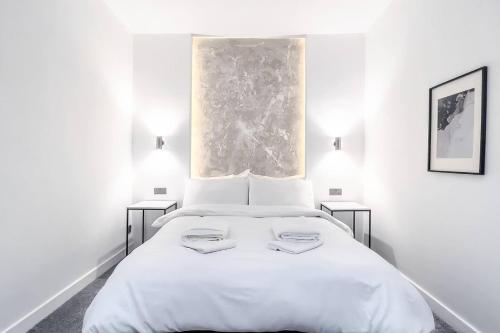 a white bedroom with a large bed with two lamps at Stunning Luxury Apartment Near Motherwell in Wishaw